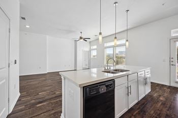 An open kitchen and living room with white walls and white counter tops and a sink